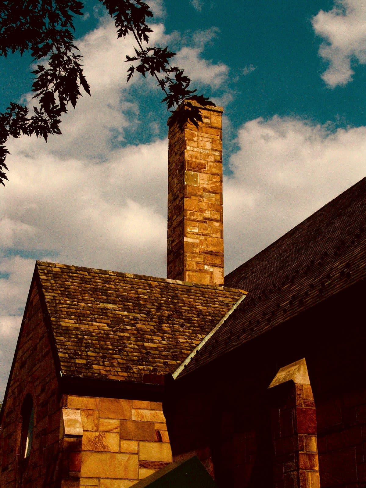A tall sandstone chimney rising against the sky on an Arts-and-Crafts house.