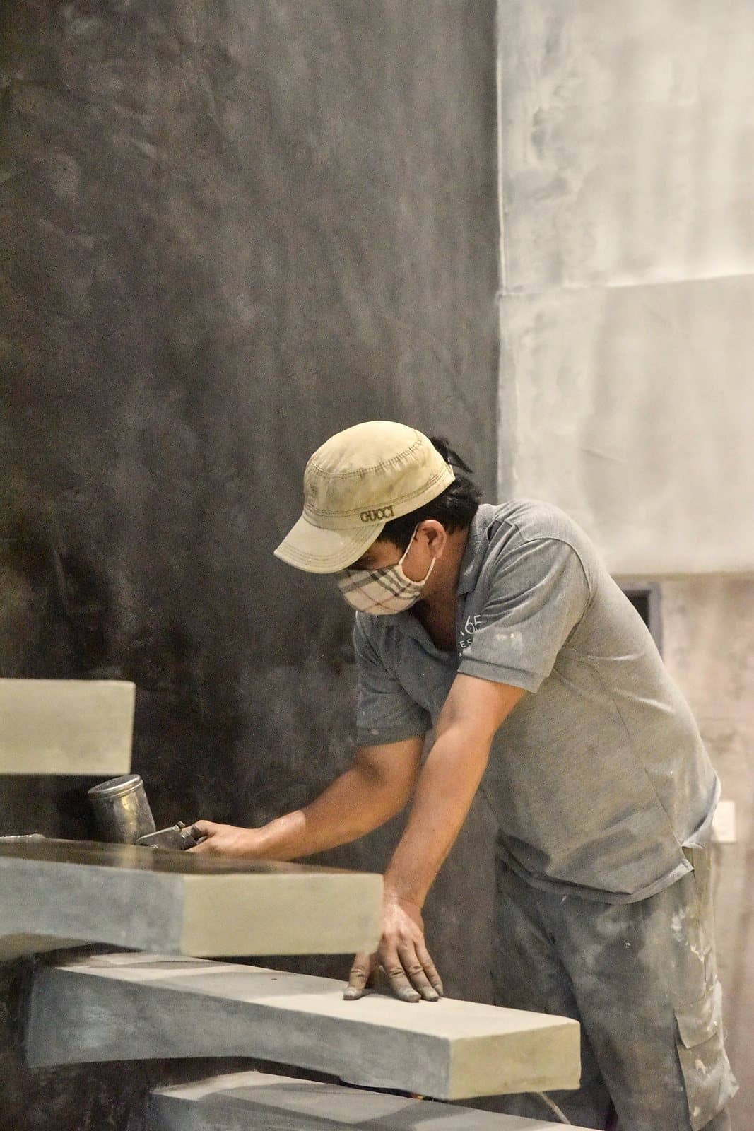 A stone worker at a workbench, shaping a slab of stone.