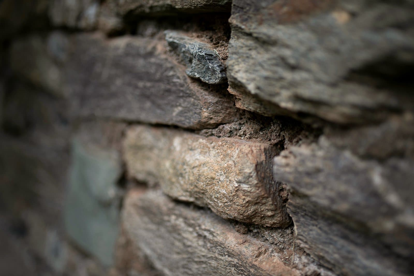 Close-up of a dry stone wall, warm brown and ochre tones, shallow focus.